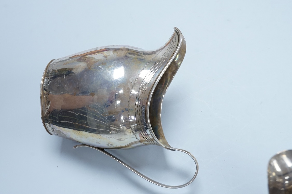 A George III silver cream jug, of oval form, London, 1801, 11cm, a George III silver helmet shaped cream jug, London, 1793, a George III small silver sugar pail, London, 1799 and a George V silver 'whisky' label, 8.4oz.